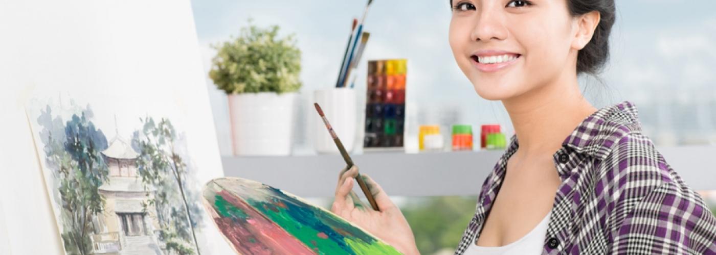 Student artist smiling with paint brush and paint palette